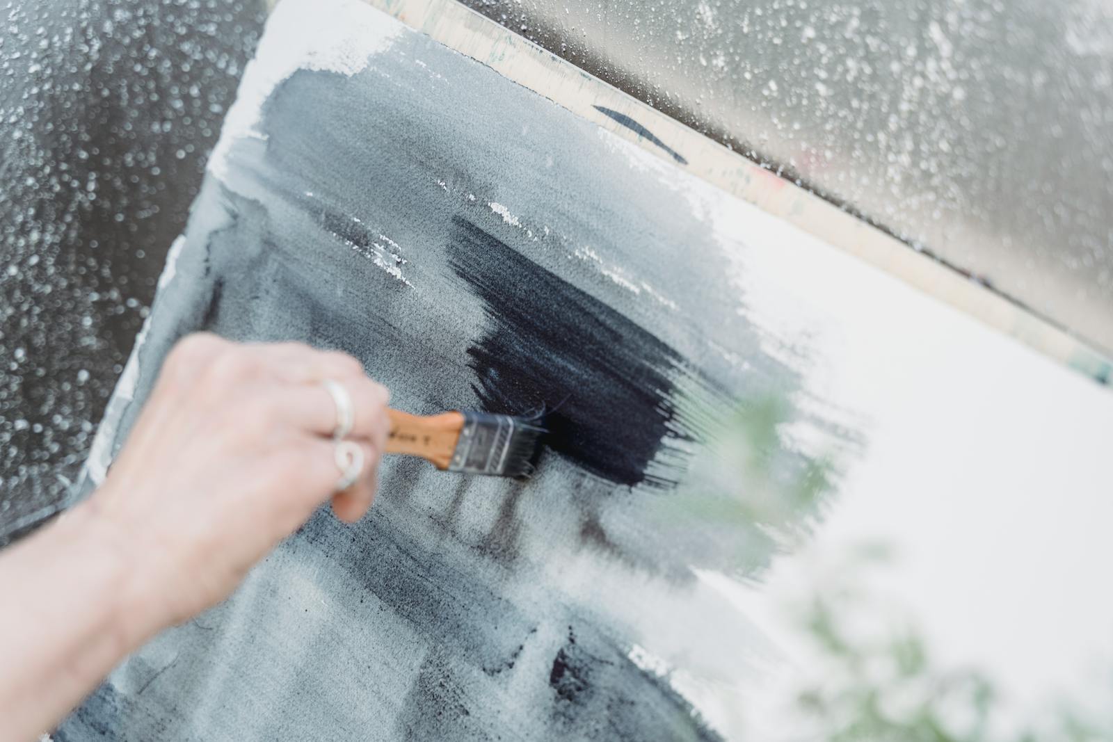 A close-up view of an artist painting with brush strokes on a canvas, showcasing creativity.