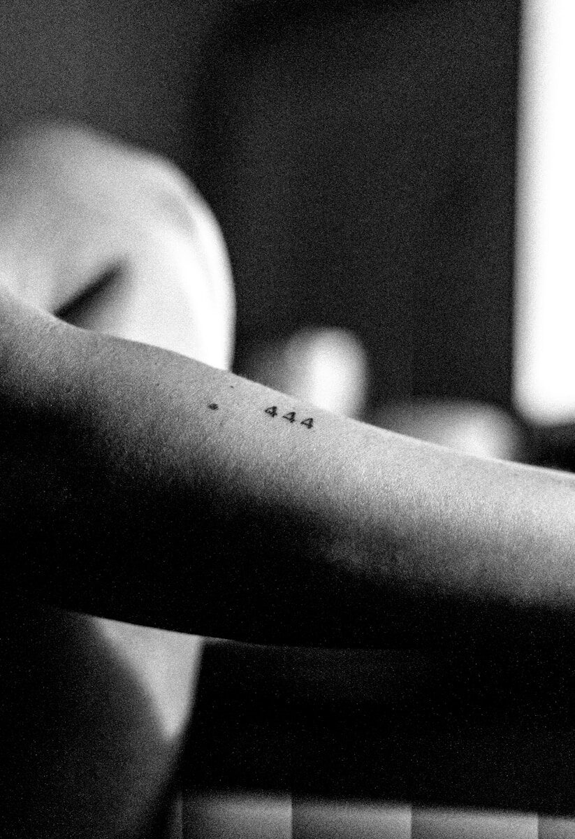 Arm with a small "444" tattoo in black and white.